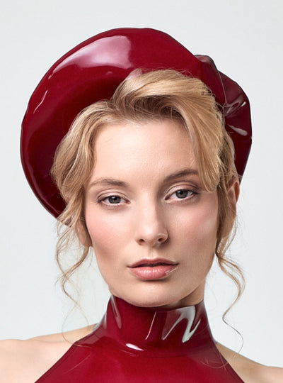 Model wearing the Artiste Latex Béret in Bordeaux, made of thicker latex for a sculptural shape. Also available in Aubergine, Black and Classic Red. Handcrafted in Berlin.