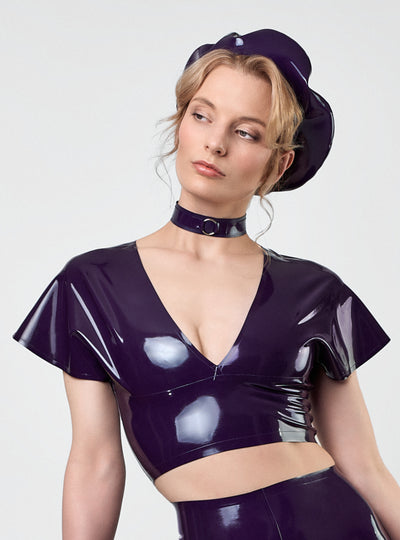 Model wearing the Juliet Latex Crop Top in Aubergine with cap sleeves and reversible V-neckline, styled with Artisté Béret, Alice Choker and High Waist Leggings. Handcrafted in Berlin.